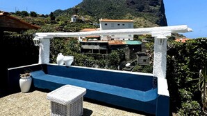 A rooftop terrace with a blue and white color scheme, a white pergola, and a view of a mountain and buildings in the background. - Studio in Porto da Cruz With Ocean Views (Machico)