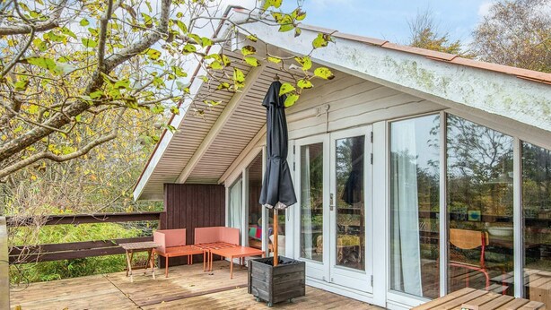 A wooden deck with outdoor seating, a covered area, and a glass door leading to a room. - 5 Person Holiday Home in Knebel (Knebel)