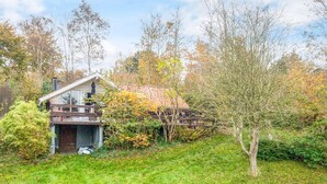 A modern house with a glass facade, a wooden deck, and a lush garden. - 5 Person Holiday Home in Knebel (Knebel)