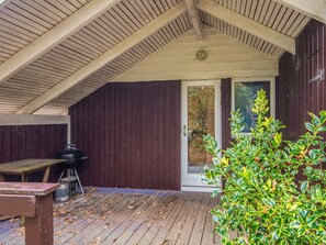 A covered outdoor area with a wooden deck, a grill, and a door leading to a glass door. - 5 Person Holiday Home in Knebel (Knebel)