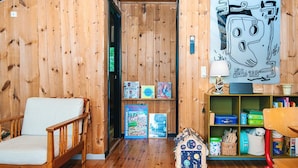 A wooden interior with a white chair, a bookshelf, and a small model house. - 5 Person Holiday Home in Knebel (Knebel)