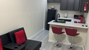 A compact living space with a kitchenette, a black sofa with red cushions, and a small bar area with two red bar stools. - 1,2,3,4 Escape comfort & style. You'll love it!" (Las Vegas)