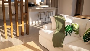 Ein modernes Wohnzimmer mit einem weißen Sofa, einer Holzleiter und einer Küche im Hintergrund.