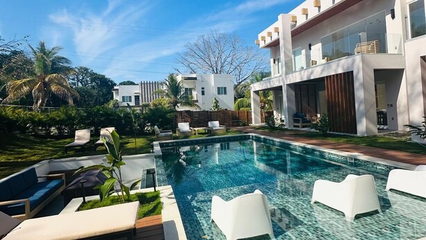 Ein moderner Poolbereich mit klarem, blauem Wasser, umgeben von weißen Liegestühlen und einer Holzterrasse.