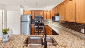 Eine Küche mit Granit-Arbeitsplatten, Edelstahlgeräten, Holzschränken und einer Spritzschutzverkleidung.