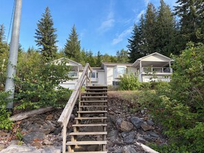 A wooden staircase leading to a row of white mobile homes surrounded by dense forest.