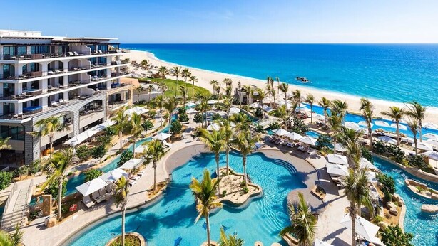 Un resort con una amplia zona de piscina, múltiples piscinas y vista al mar.