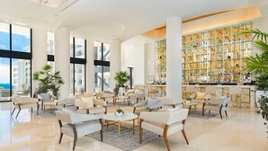Un lobby espacioso con zona de bar, asientos y amplias ventanas con vistas.