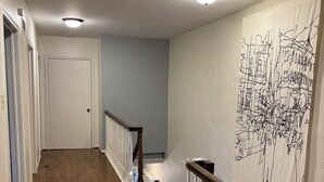 Un couloir doté d’un plancher en bois, de murs blancs et d’un escalier avec des rampes blanches.