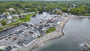 An aerial view of a coastal town with a marina, houses, and a bridge.