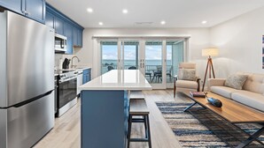 A modern kitchen with a large island, stainless steel appliances, and a view to the outside.