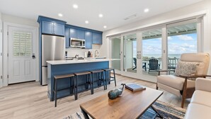 A modern kitchen with blue cabinets, a stainless steel refrigerator, and a bar area.