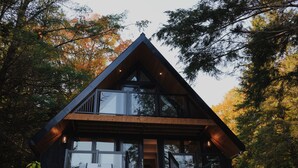 A modern cabin with a large balcony, a wooden deck, and a grill area. - A-Frame retreat with hot tub, sauna (Huntsville)