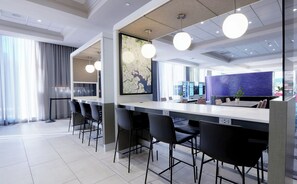 A modern hotel lobby with a long reception desk, black chairs, a large map on the wall, and a blue textured wall in the background. - Chase at Baltimore Harbor (Baltimore)