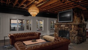 A spacious living room with a stone fireplace, leather sofas, and large windows offering a view of the outdoors. - evo Hotel Tahoe City (Tahoe City)