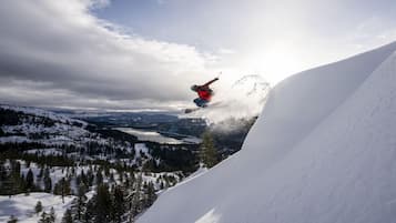A snowboarder performing a jump over a snow-covered slope with a mountainous landscape in the background.