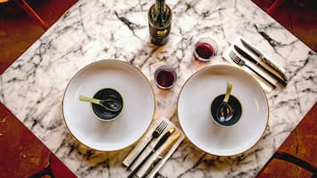 Une table en marbre avec deux assiettes, des couverts et une bouteille de vin.