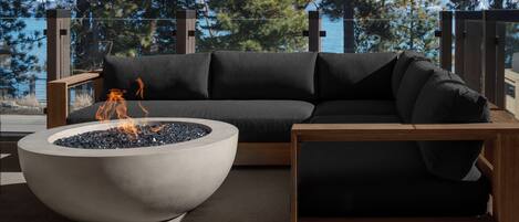 A modern outdoor seating area with a concrete fire pit and a dark-colored sofa.