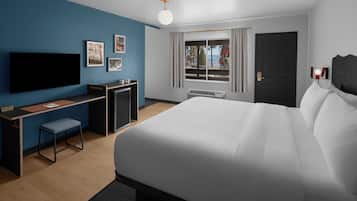 Quarto de hotel moderno com uma cama grande, uma escrivaninha, televisão de tela plana e janela com cortinas.