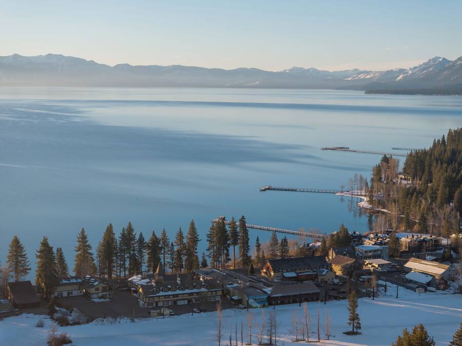 A lakeside resort with multiple buildings, a dock, and snow-covered surroundings.