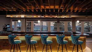 A bar area with a wooden ceiling, large windows, and blue bar stools. - evo Hotel Tahoe City (Tahoe City)