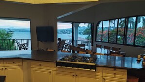 A kitchen with a gas stove, white cabinets, and a view of the sea through large windows. - Room in House - Dream House on Lake Tequesquitengo (Jojutla)