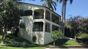 A two-story building with balconies, surrounded by palm trees and greenery. - Room in House - Dream House on Lake Tequesquitengo (Jojutla)
