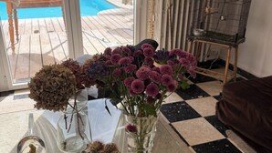 Une table en verre ornée d’un cactus, de fleurs séchées et d’un vase contenant des fleurs roses.