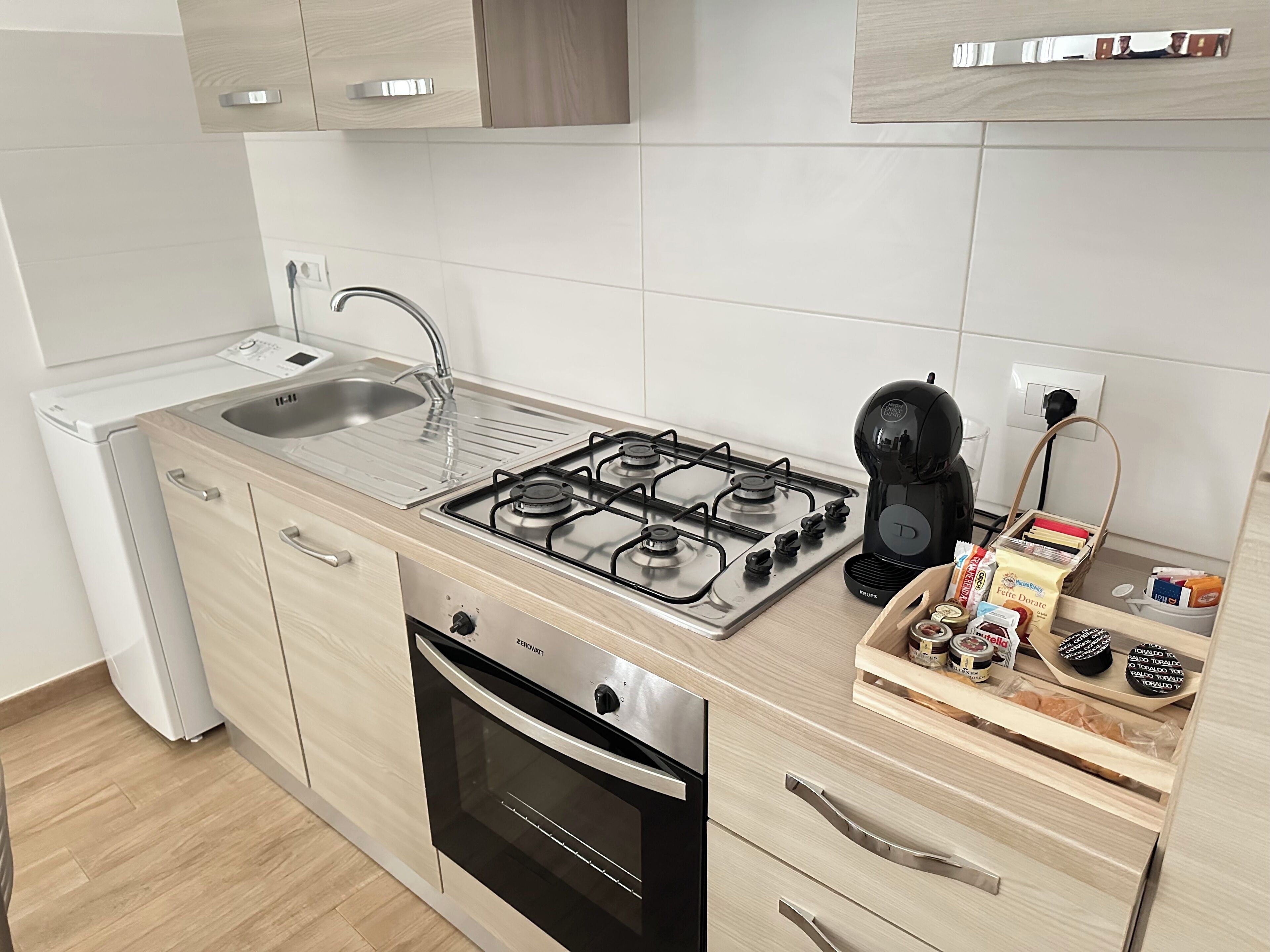 Cocina compacta con estufa a gas, horno y cafetera.