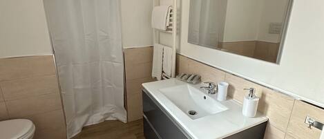 Un baño moderno con inodoro, lavabo y cabina de ducha.