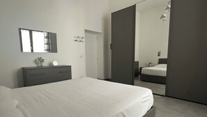 A modern bedroom with a bed, bedside table, mirror, and wardrobe. - TOI Apartments (Brindisi)