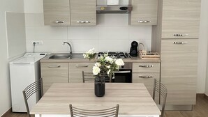 A modern kitchen with light wood cabinetry, a built-in stove, and a small refrigerator. - TOI Apartments (Brindisi)