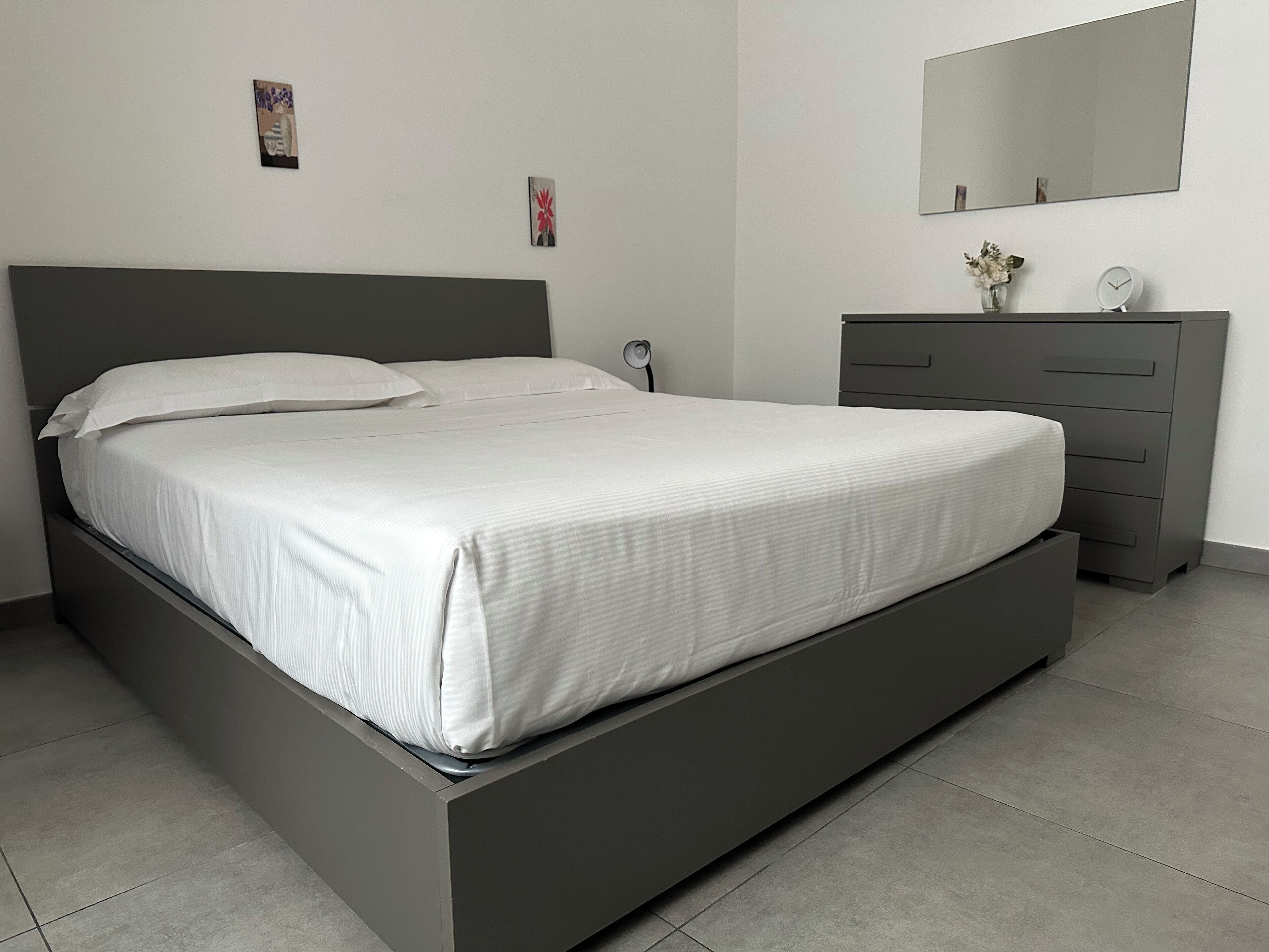 Een moderne slaapkamer met een bed, een dressoir en een spiegel.