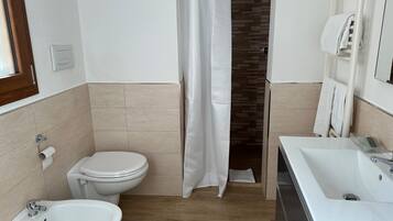 A bathroom with a toilet, bidet, and sink.