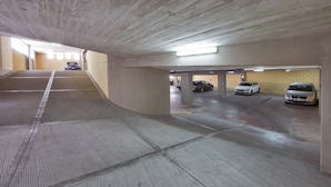 An underground parking garage with concrete walls and a sloped ceiling. - TOI Apartments (Brindisi)