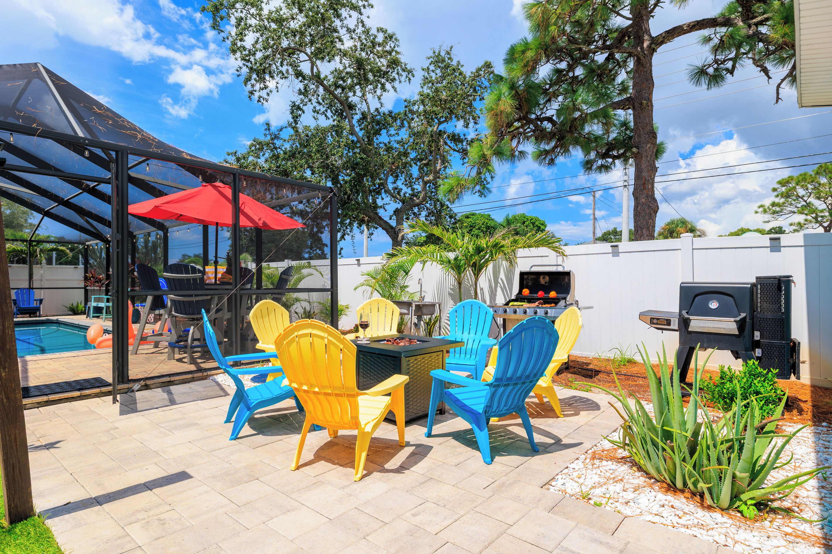 An outdoor patio with a covered seating area, a barbecue grill, and a swimming pool.