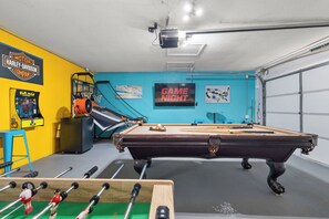 Une pièce équipée d’une table de billard, d’un baby-foot, de jeux d’arcade et d’un panneau indiquant « SOIRÉE JEUX ».