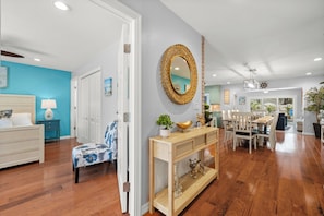 A spacious living area with a dining table, a sofa, and a decorative mirror.