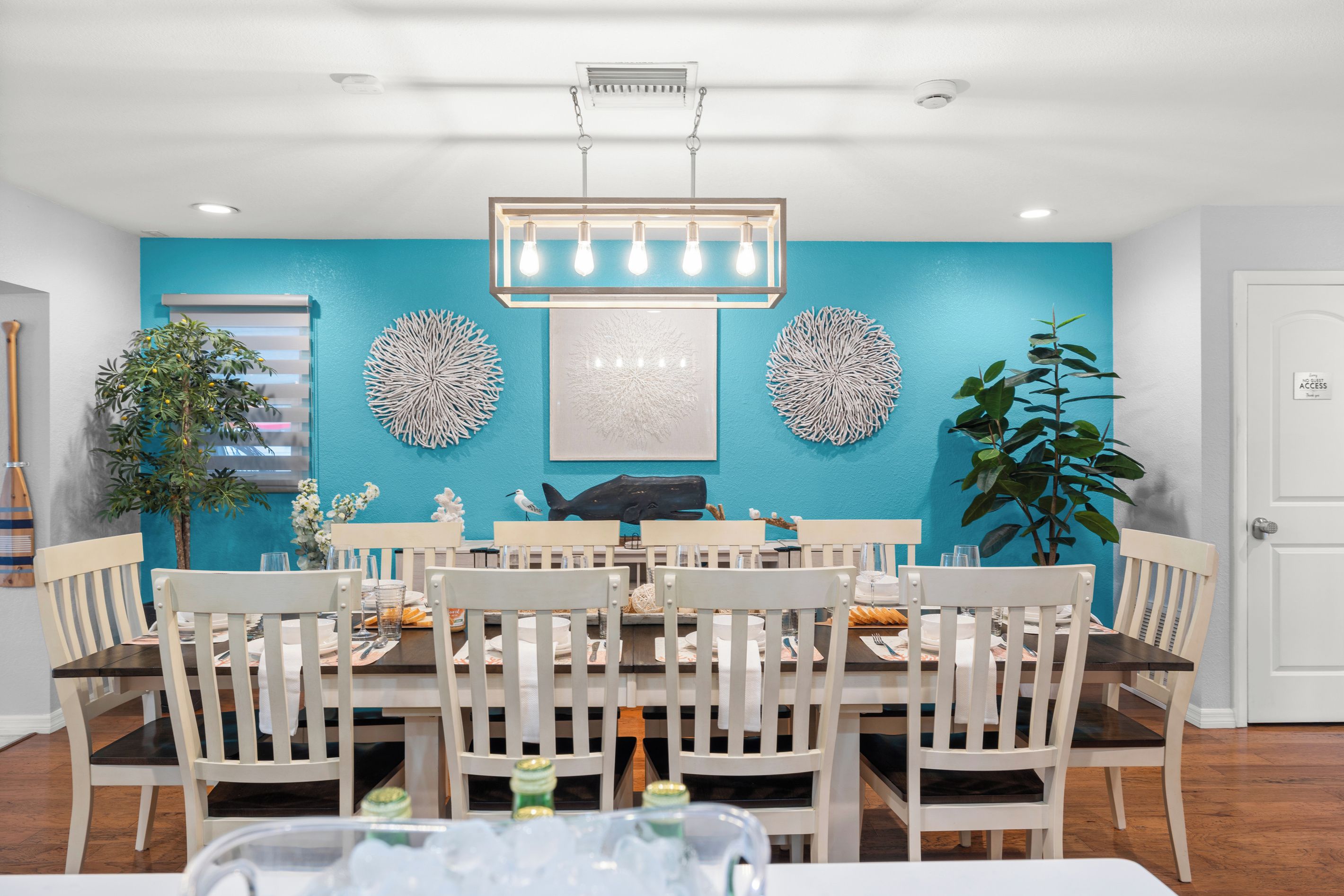 A dining area with a round table, white chairs, a blue accent wall, and decorative wall art.