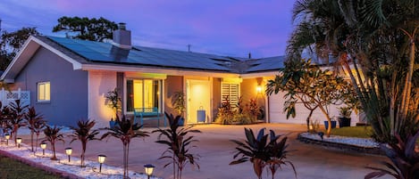 Une maison moderne dotée d’un porche abrité, de panneaux solaires et d’une allée bien éclairée.