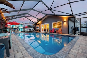 Indendørs swimmingpool med glasloft, omgivet af liggestole og en bar.