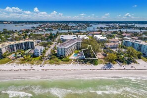 Eine Luftaufnahme einer Küstenlandschaft mit mehreren Hotelgebäuden, einem Strand und einer großen Wasserfläche.