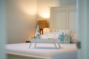 A bed with a tray holding a bottle and glasses, a pillow with a blue design, and a lamp in the background. - Screened Heated Pool, 15 Min to Beach | 4BR Sleeps 10, Largo (Largo)