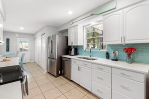 A modern kitchen with white cabinets, a stainless steel refrigerator, a dishwasher, and a window with a view. - Screened Heated Pool, 15 Min to Beach | 4BR Sleeps 10, Largo (Largo)