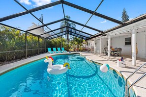 Une piscine dotée d’un toit en verre, entourée de chaises longues et d’un espace patio couvert.