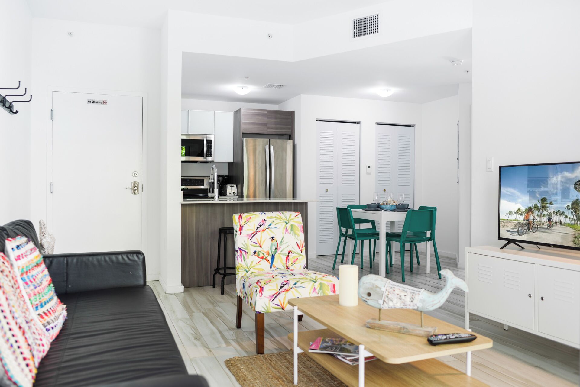 A compact living space with a sofa, a dining table with chairs, a kitchen area, and a television.