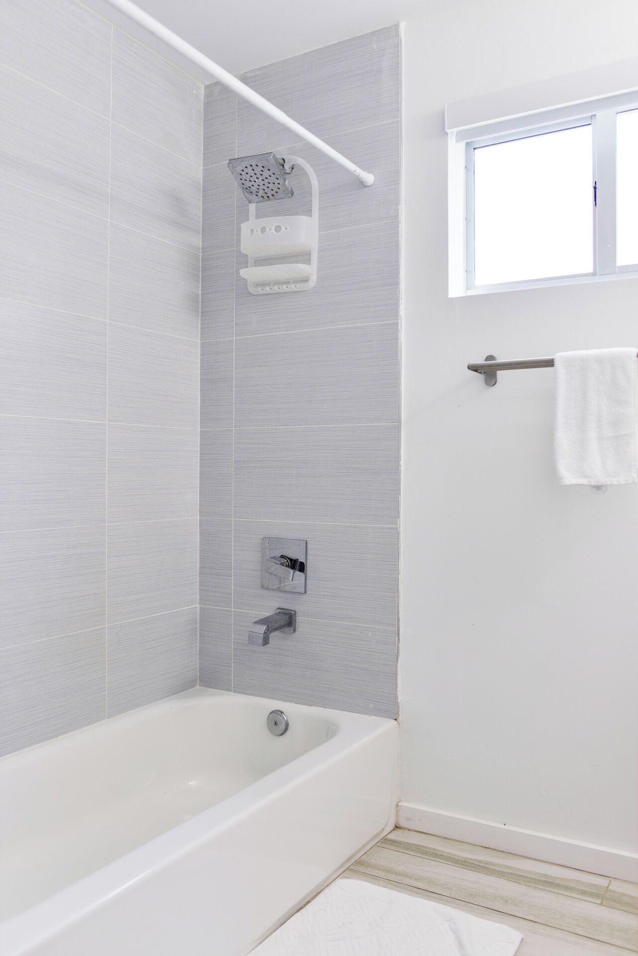 A modern bathroom with a bathtub, a showerhead, and a towel rack.