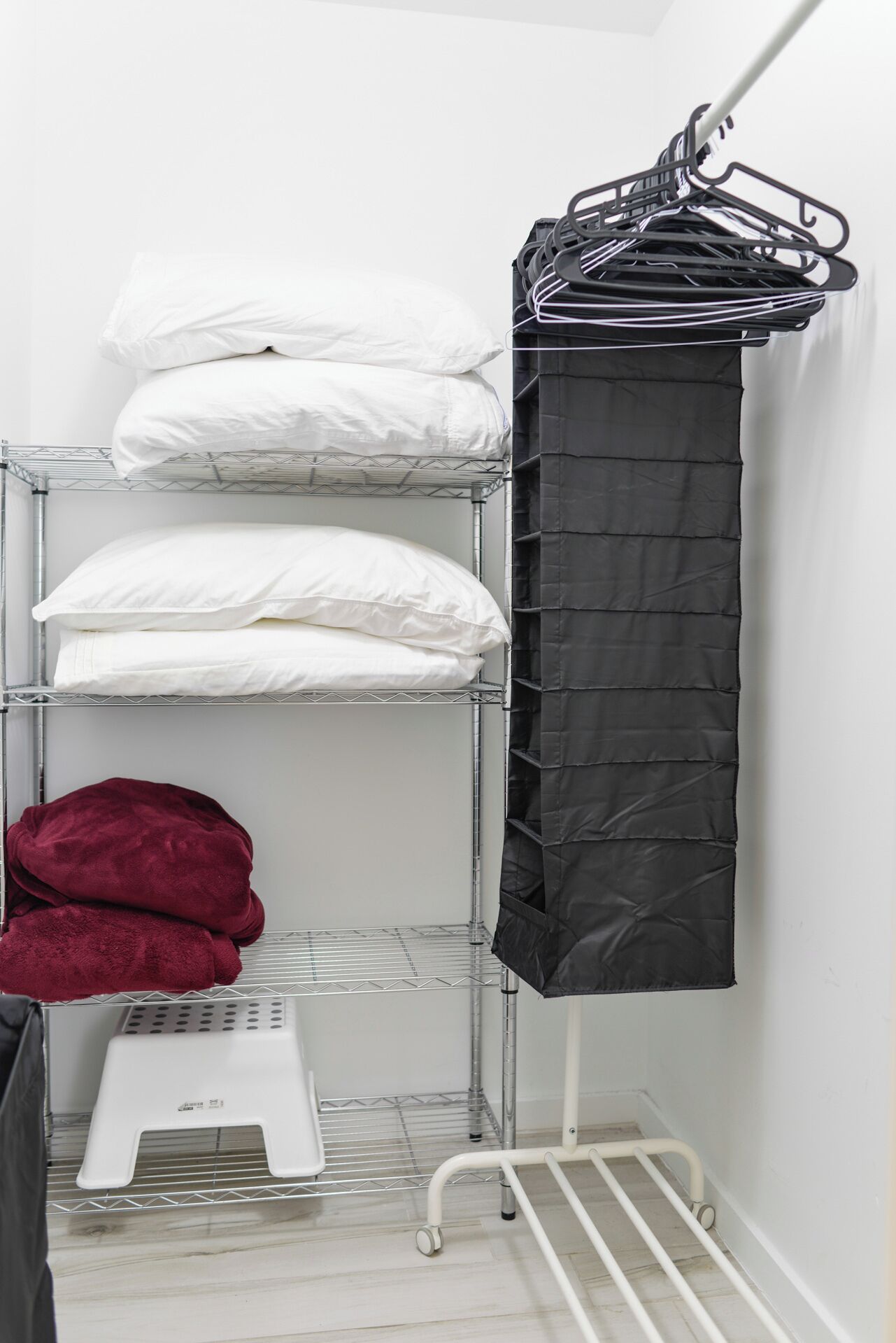 A metal shelf unit with white and black linens, a red towel, and a black curtain.