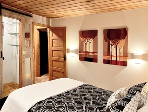Een slaapkamer met een bed, een houten deur en twee wandlampen.