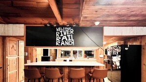 Eine rustikale Küche mit Barbereich, Holzausstattung und einem Kreidetafel-Schild mit der Aufschrift 'WELCOME TO RIVER RANCH'.